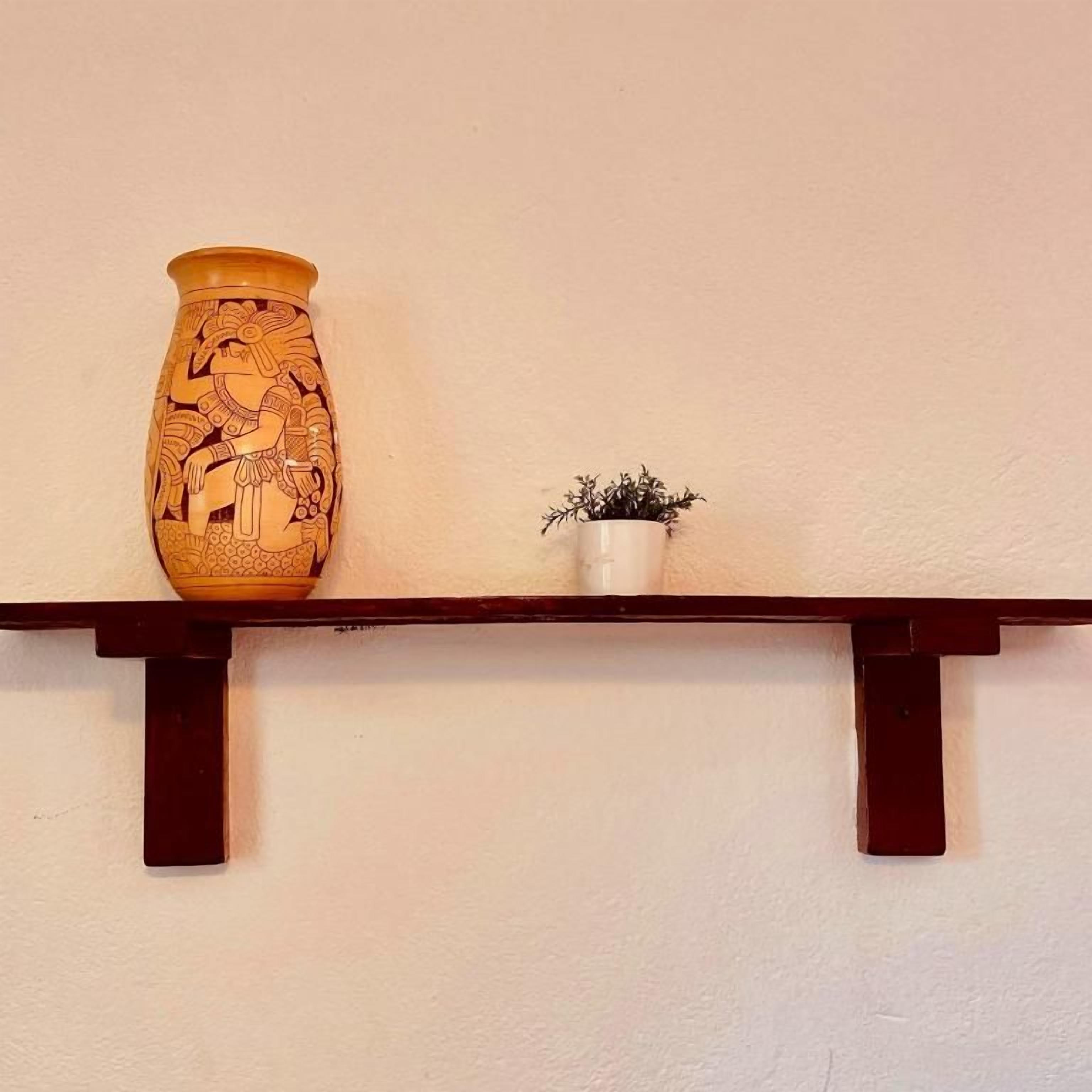 Ein Regal mit einer großen Vase und einem kleinen Topfpflanzen.
