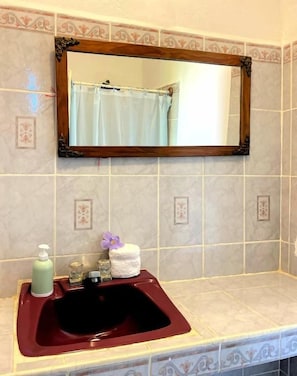 A bathroom with a sink, mirror, and toiletries. - Casita de Playa Bomalu (Las Peñitas)