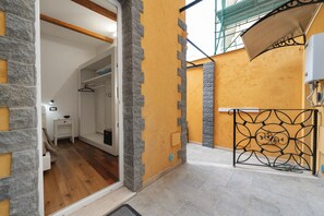 A room with a stone wall, a metal gate, and a wooden floor. - Empathy House – Room 1 (Cagliari)