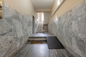 A marble-floored hallway with a staircase leading to a door at the end. - Empathy House – Room 2 (Cagliari)