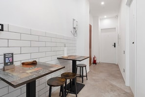 A narrow hallway with a white tiled wall, a wooden door, and a fire extinguisher. - Empathy House – Room 2 (Cagliari)