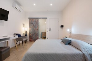 A modern hotel room with a bed, desk, chair, and a television. - Empathy House – Room 3 (Cagliari)
