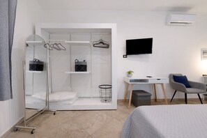 A modern bedroom with a walk-in closet, a desk, a chair, a TV, and a bed. - Empathy House – Room 3 (Cagliari)