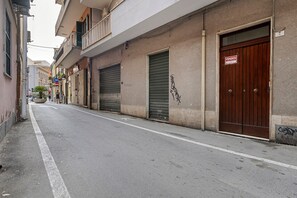 Une rue étroite, bordée de boutiques fermées, et une porte en bois avec une enseigne.