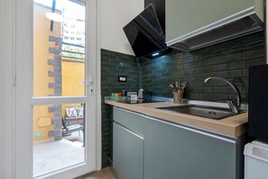 A kitchen with a built-in oven, a sink, and a window overlooking a balcony. - Empathy House – Room 3 (Cagliari)