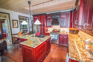 A kitchen with a large island, wooden cabinets, and a stainless steel range hood. - 5 minute boat ride from harbour front .superb fishing or swim off the dock . (Kenora)