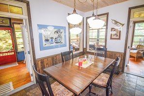 A dining area with a wooden table, chairs, pendant lights, and artwork on the walls. - 5 minute boat ride from harbour front .superb fishing or swim off the dock . (Kenora)