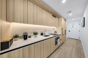 Eine moderne Küche mit Holzschränken, einem eingebauten Ofen und einer Edelstahl-Spüle.