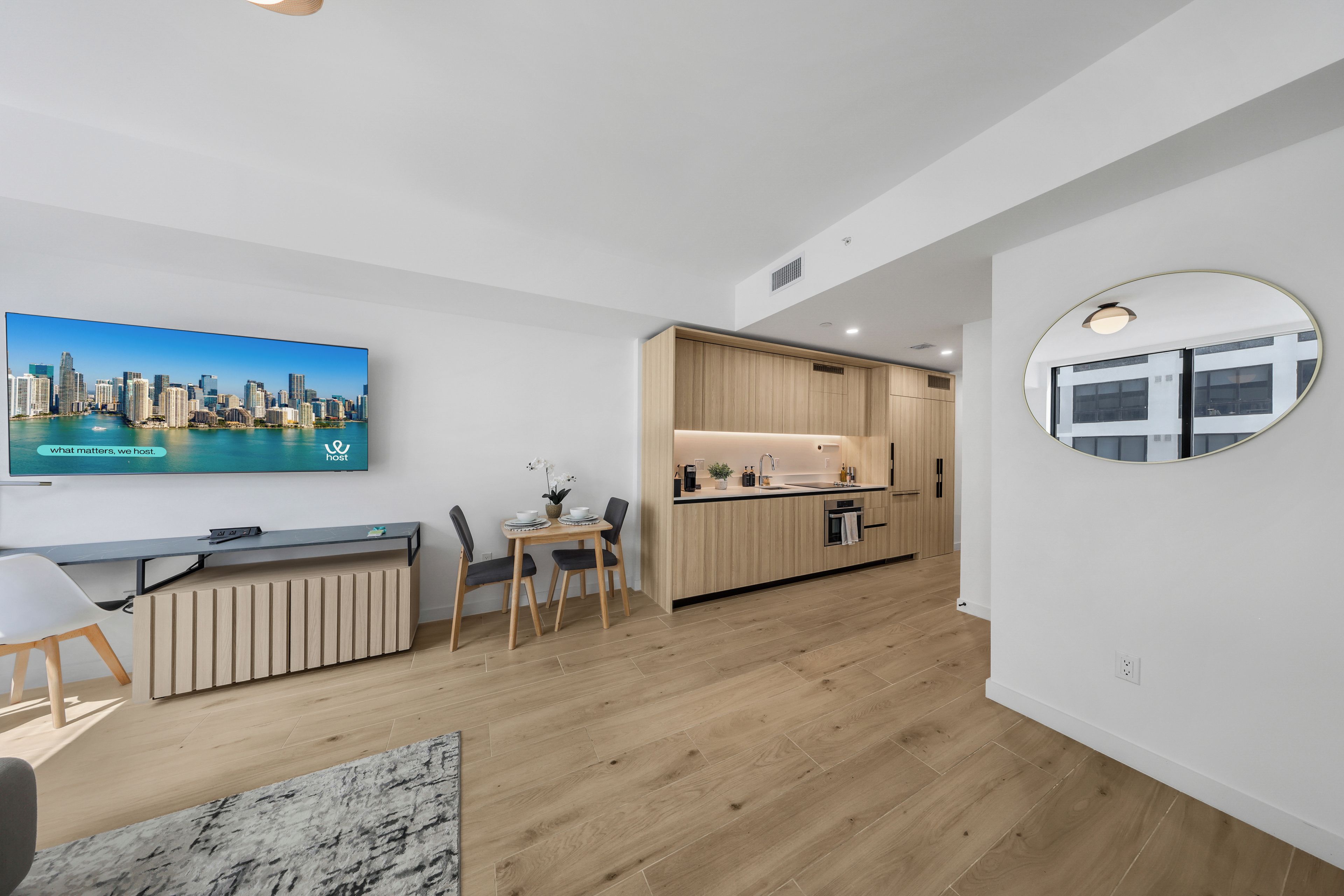 Ein modernes Apartment mit Küche, Essbereich und einem Fernseher, der eine Stadtansicht zeigt.