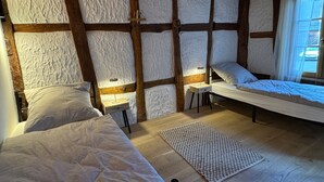 Une chambre avec deux lits, une petite table et une fenêtre avec des rideaux.