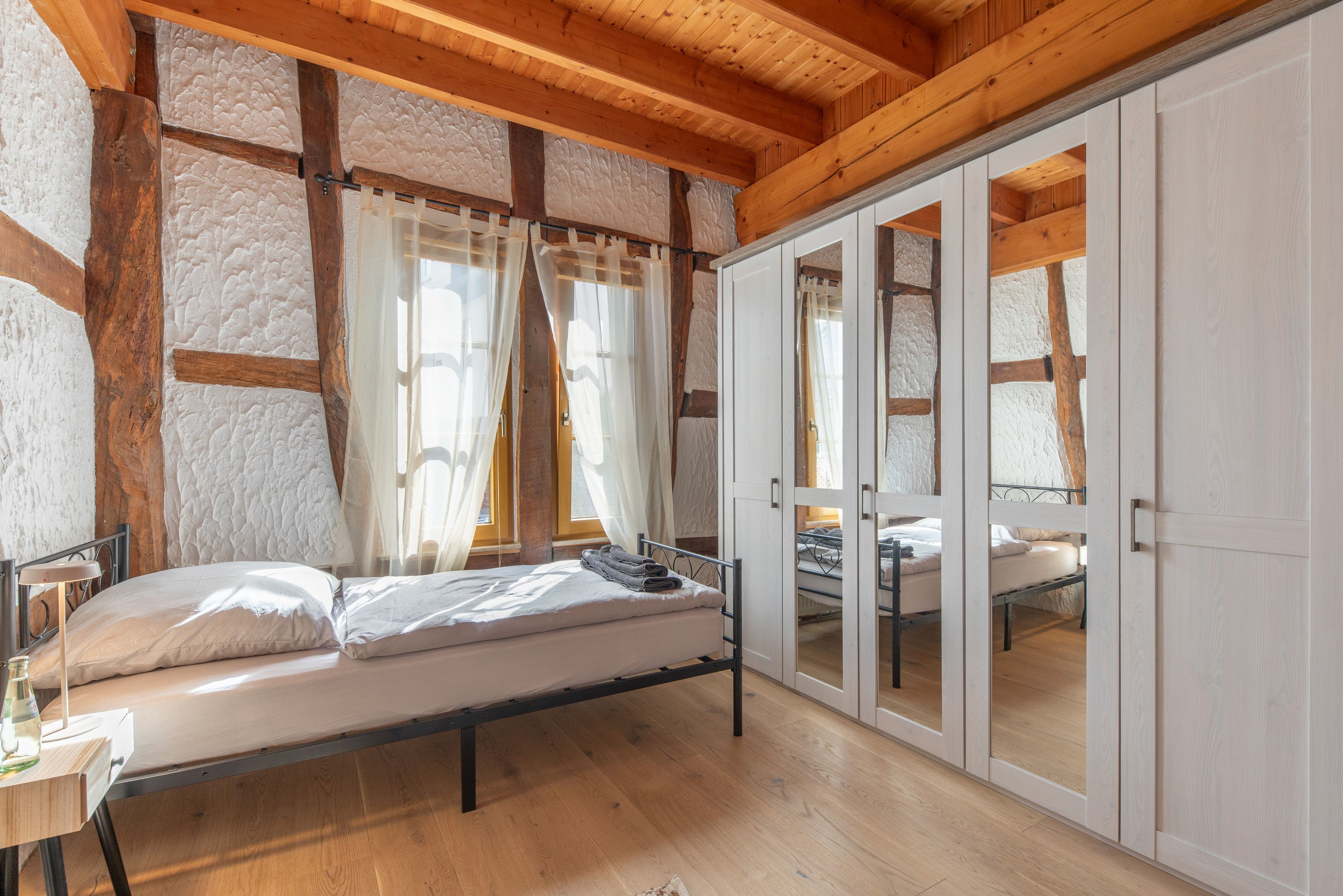A bedroom with a bed, a desk, and a wardrobe.