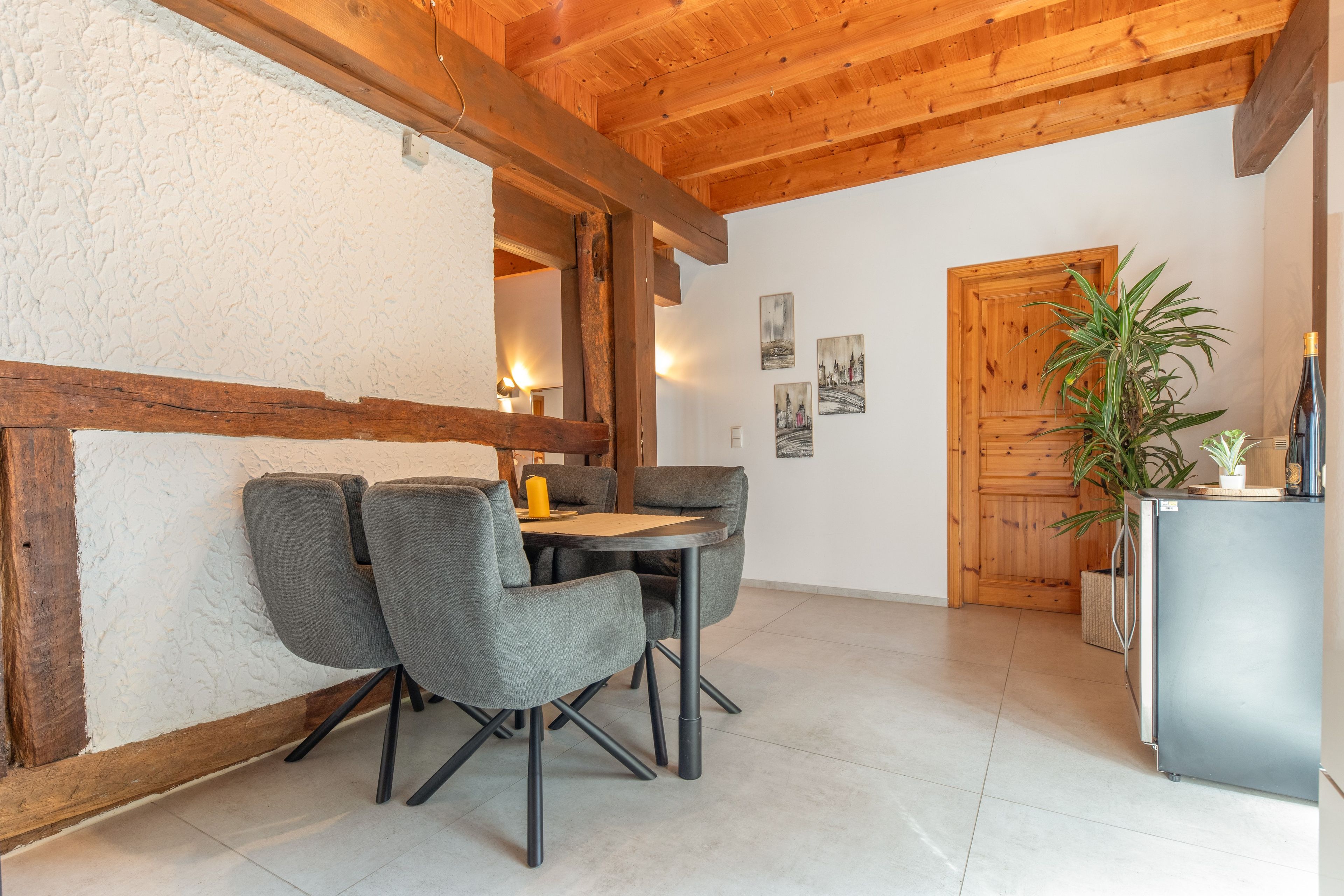 Un espace repas doté d’un plafond en bois, d’une table avec des chaises et d’un réfrigérateur.