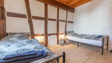Une chambre avec deux lits, un plafond en bois et un mur à la texture particulière.
