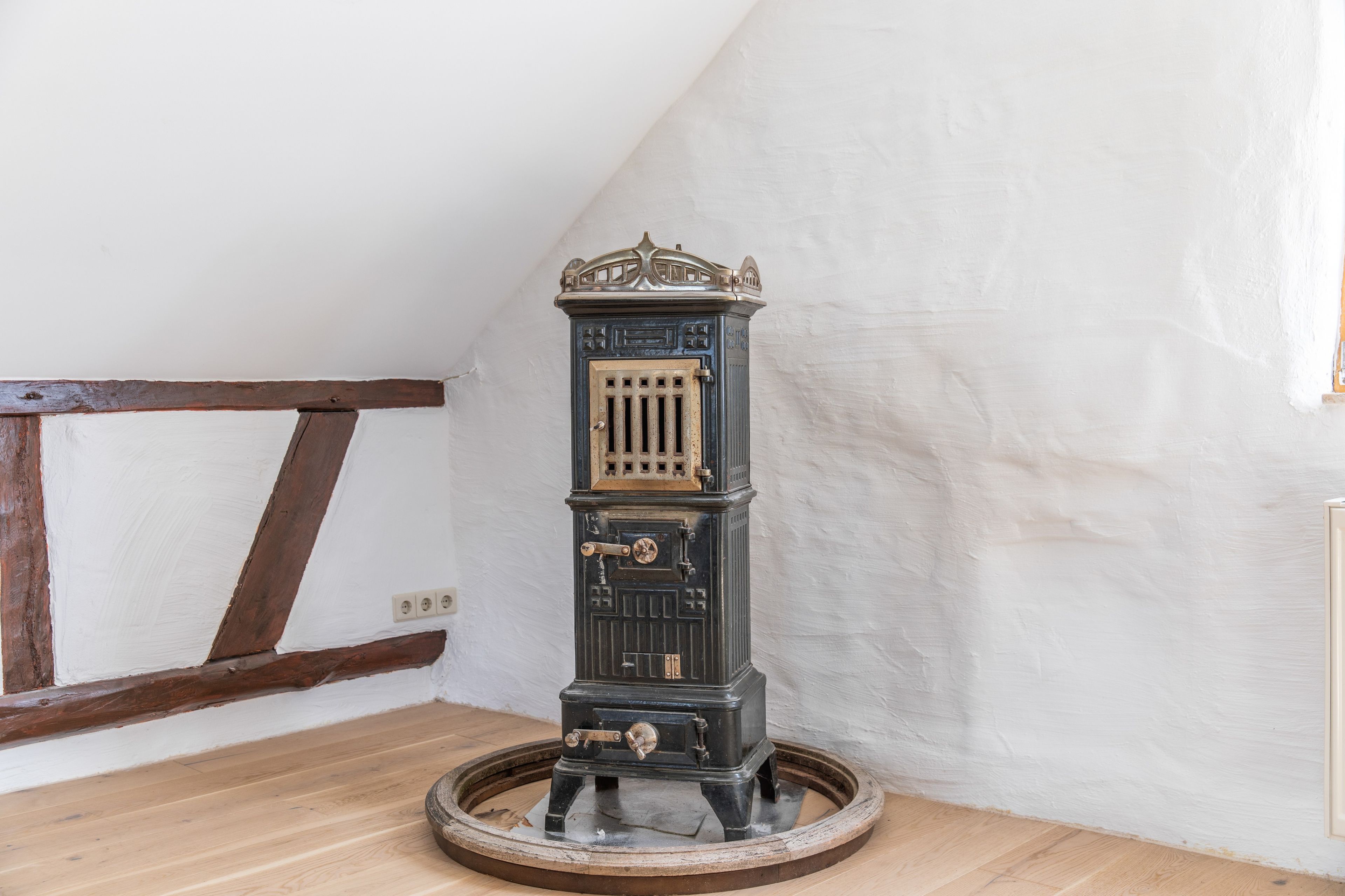 A vintage stove with a decorative top, a front door with a lock, and a circular base.