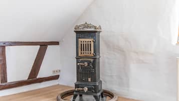 A vintage stove with a decorative top, a front door with a lock, and a circular base.