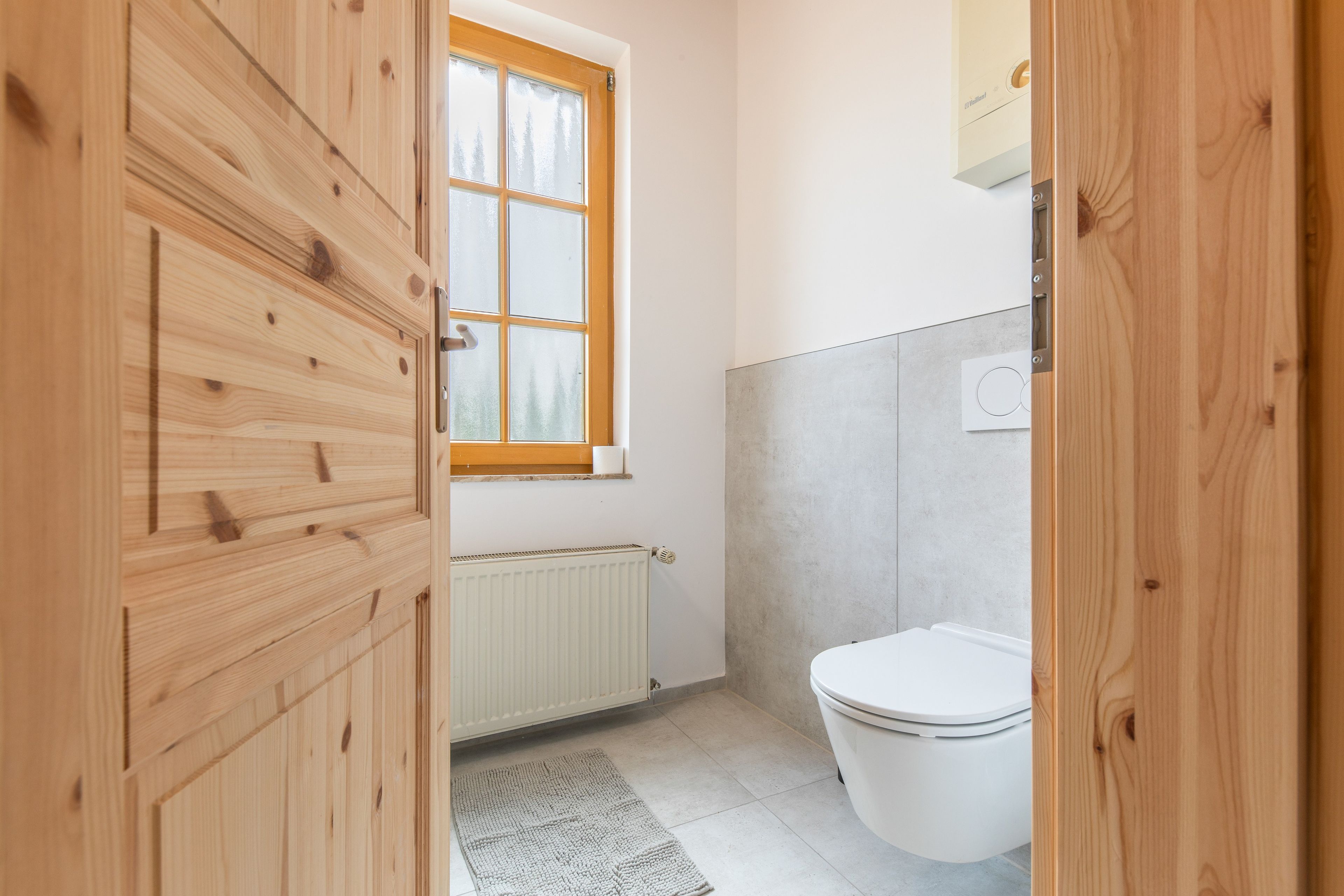 A bathroom with a white toilet, a radiator, and a window.
