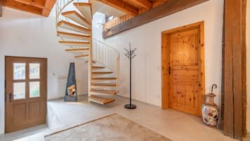 A spiral staircase with a wooden finish, a large wooden door, and a decorative vase.