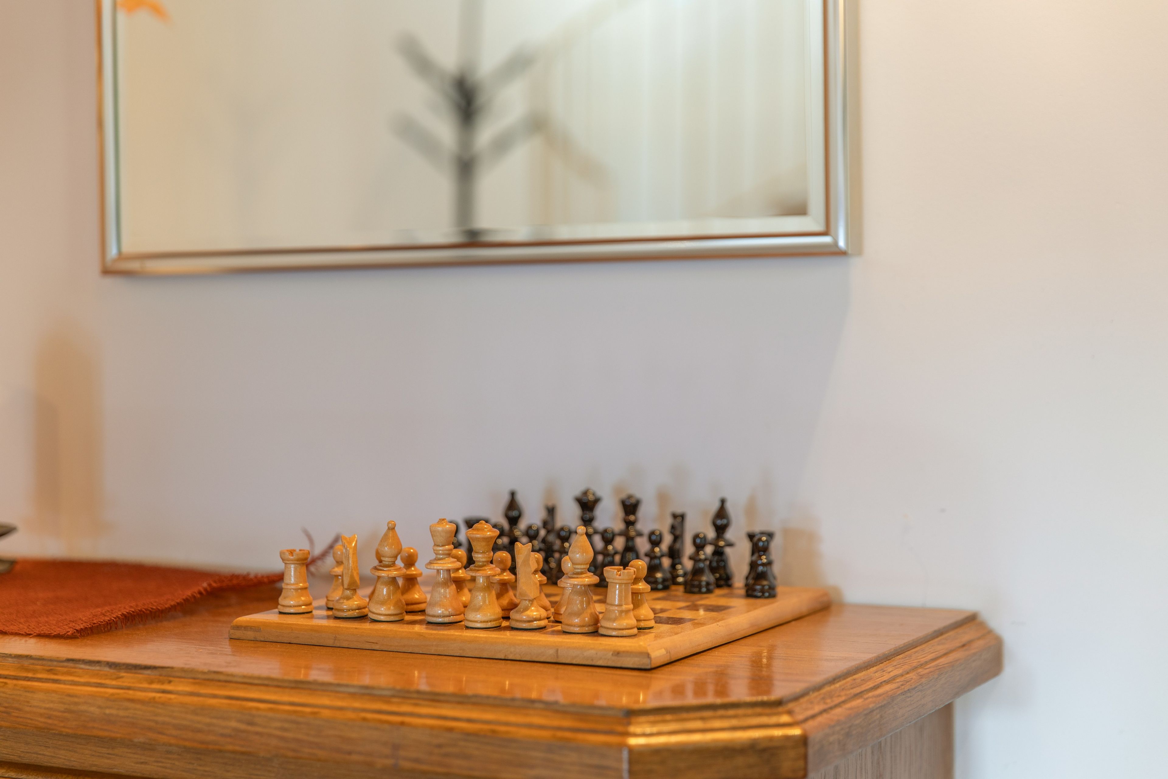 A chessboard on a wooden table with a framed picture above it.