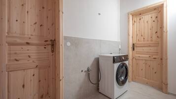 Ein Waschraum mit Holztüren, einer Waschmaschine und einer gefliesten Wand.