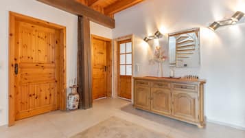 Un couloir avec des portes en bois, un miroir, une armoire et un vase.