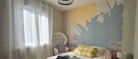 Ein Schlafzimmer mit einem Bett, einem Sessel, einer Lampe und einem Wandbild.