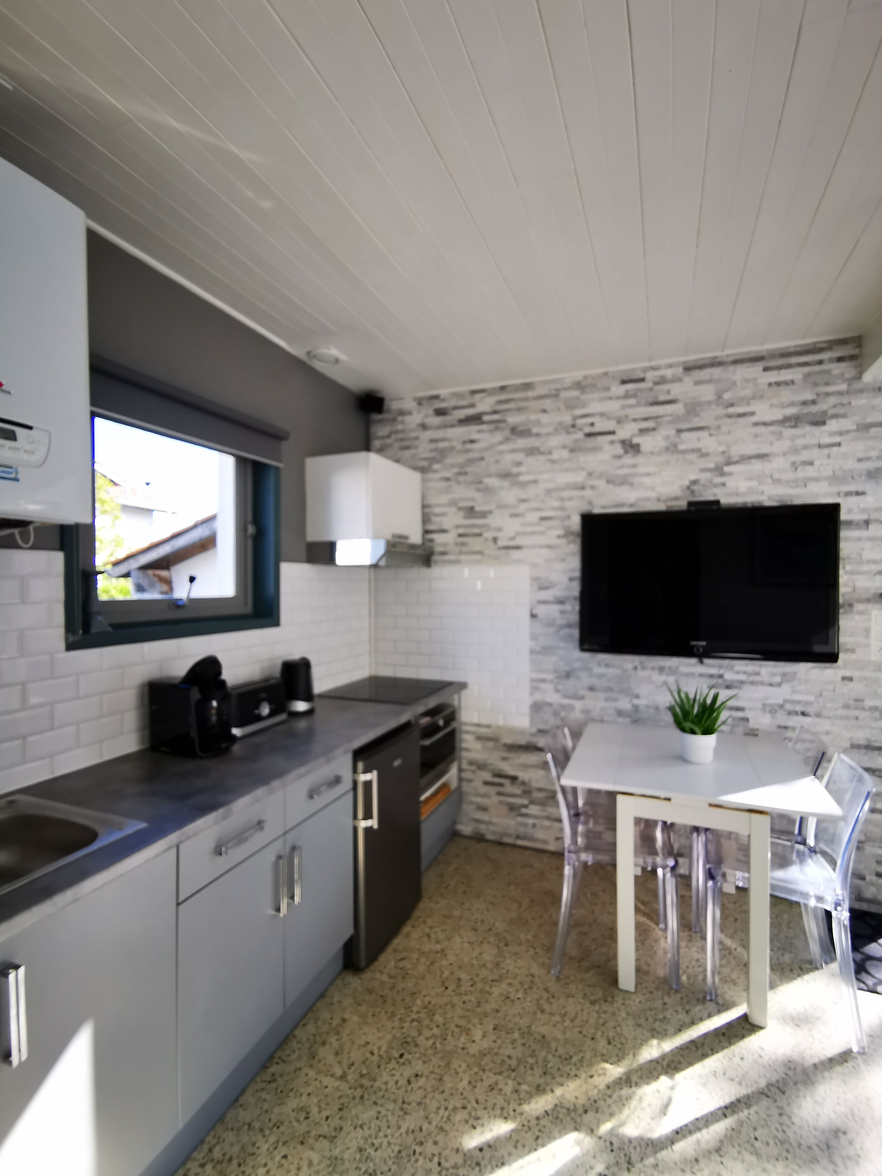 A modern kitchen with a granite countertop, white cabinetry, a built-in oven, and a window.