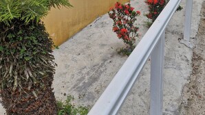 A yellow building with a white window, a white railing, and red flowers. - VILLA 972 MARINE (Le Vauclin)
