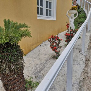 Un edificio giallo con una finestra bianca, una ringhiera bianca e fiori rossi.