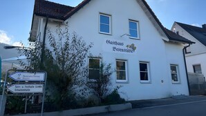 A white building with a sign reading 'Gasthaus Bevenstüble' and directional signs for 'Panorama Therme Beuren' and 'Turn- u. Festhalle Schdle Schwimmhalle'.