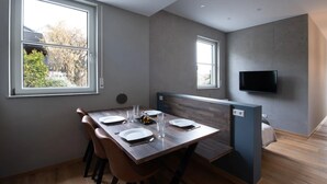 A modern dining area with a wooden table, chairs, and a television mounted on the wall.