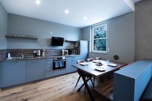 Una cocina moderna con comedor, piso de madera y un amplio ventanal con vistas a árboles.