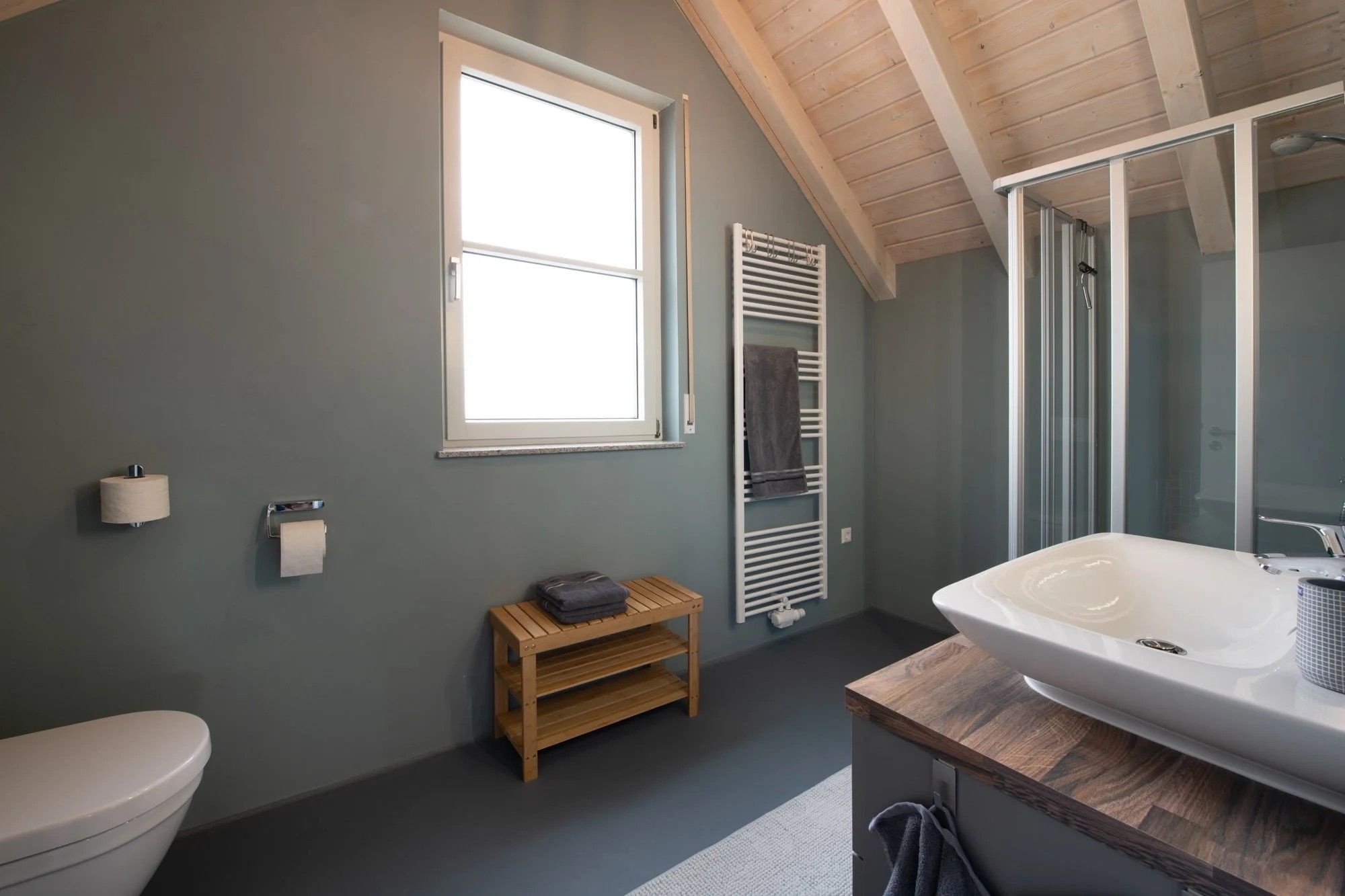 A bathroom with a toilet, a sink, a window, and a towel rack.