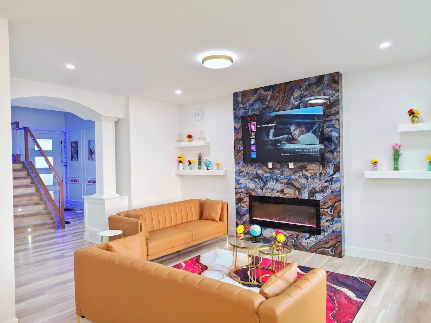 A modern living room with a sofa, a coffee table, and a flat-screen TV mounted on a marble wall.