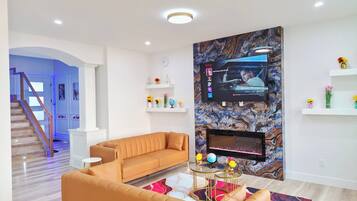 A modern living room with a sofa, a coffee table, and a flat-screen TV mounted on a marble wall.