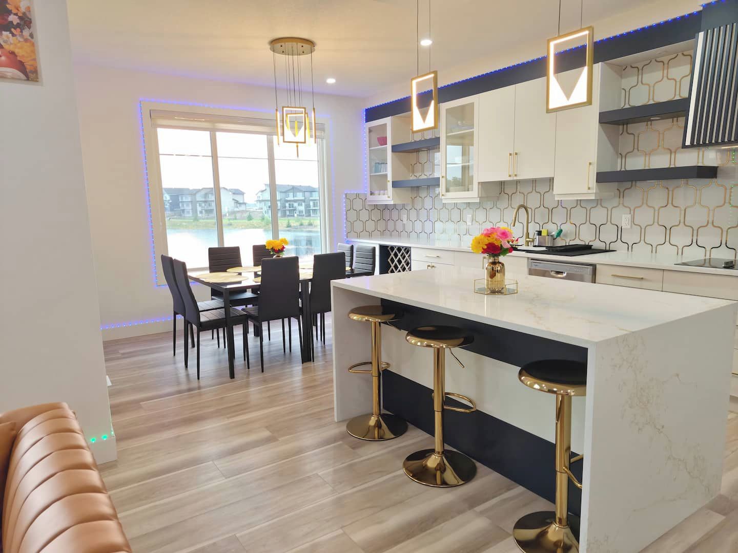 A modern kitchen with a large island, bar stools, and a dining area with a view.