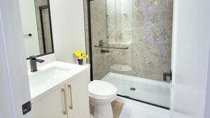 A modern bathroom with a glass-enclosed shower, a white toilet, and a vanity with gold handles. - SwitHome Properties 4BR l 3 baths Lux Escape Near YEG lPond Viewl Game l Triple car Garage. (Leduc)