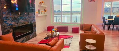 Una sala de estar moderna con chimenea, un ventanal con vistas y un comedor con mesa y sillas.