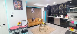A modern kitchen with a built-in oven and microwave, a dining area with a red table and chairs, and a living area with a sofa and a decorative wall. - SwitHome Properties Glen Cozy Suite Near Yeg Airport (Edmonton)