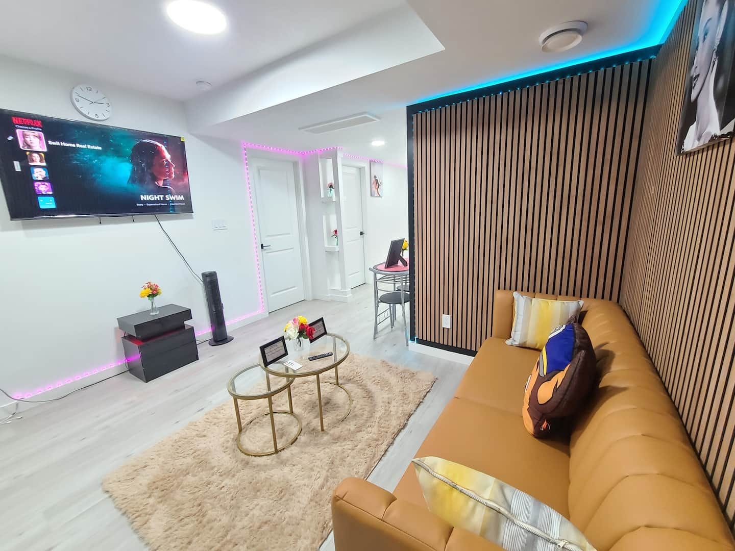 A modern living room with a flat-screen TV, a sofa, a coffee table, and a decorative wall panel.