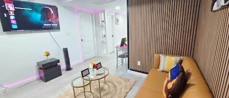 A modern living room with a flat-screen TV, a sofa, a coffee table, and a decorative wall panel.