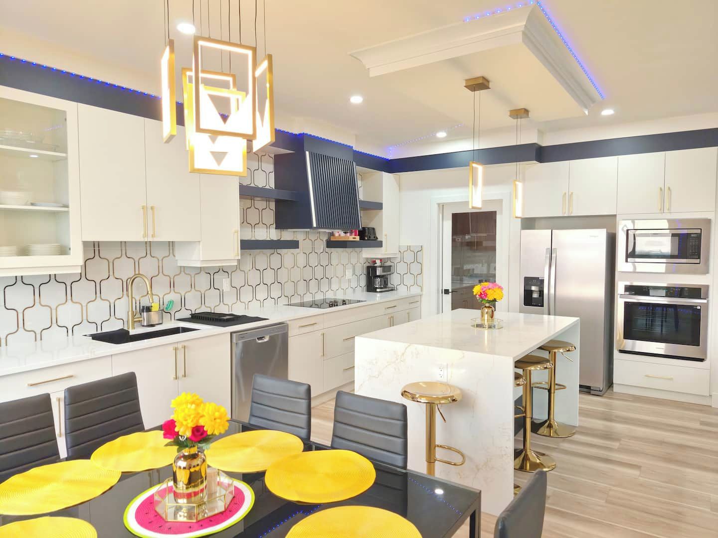 Une cuisine moderne avec des meubles blancs, un îlot central et des appareils électroménagers en acier inoxydable.