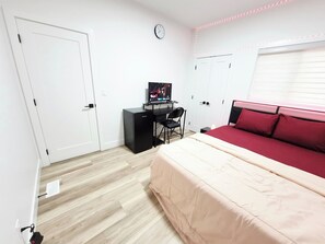 A bedroom with a bed, a desk with a computer, a chair, a clock on the wall, and a window with blinds. - SwitHome Properties Luxury 3BR l 3baths Near YEGl Pondview l Games l With Triple Car  Garage (Leduc)