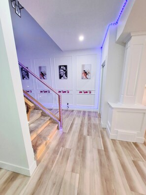 A staircase with wooden steps and a metal railing, leading to a landing with white walls and a white door. - SwitHome Properties Luxury 3BR l 3baths Near YEGl Pondview l Games l With Triple Car  Garage (Leduc)
