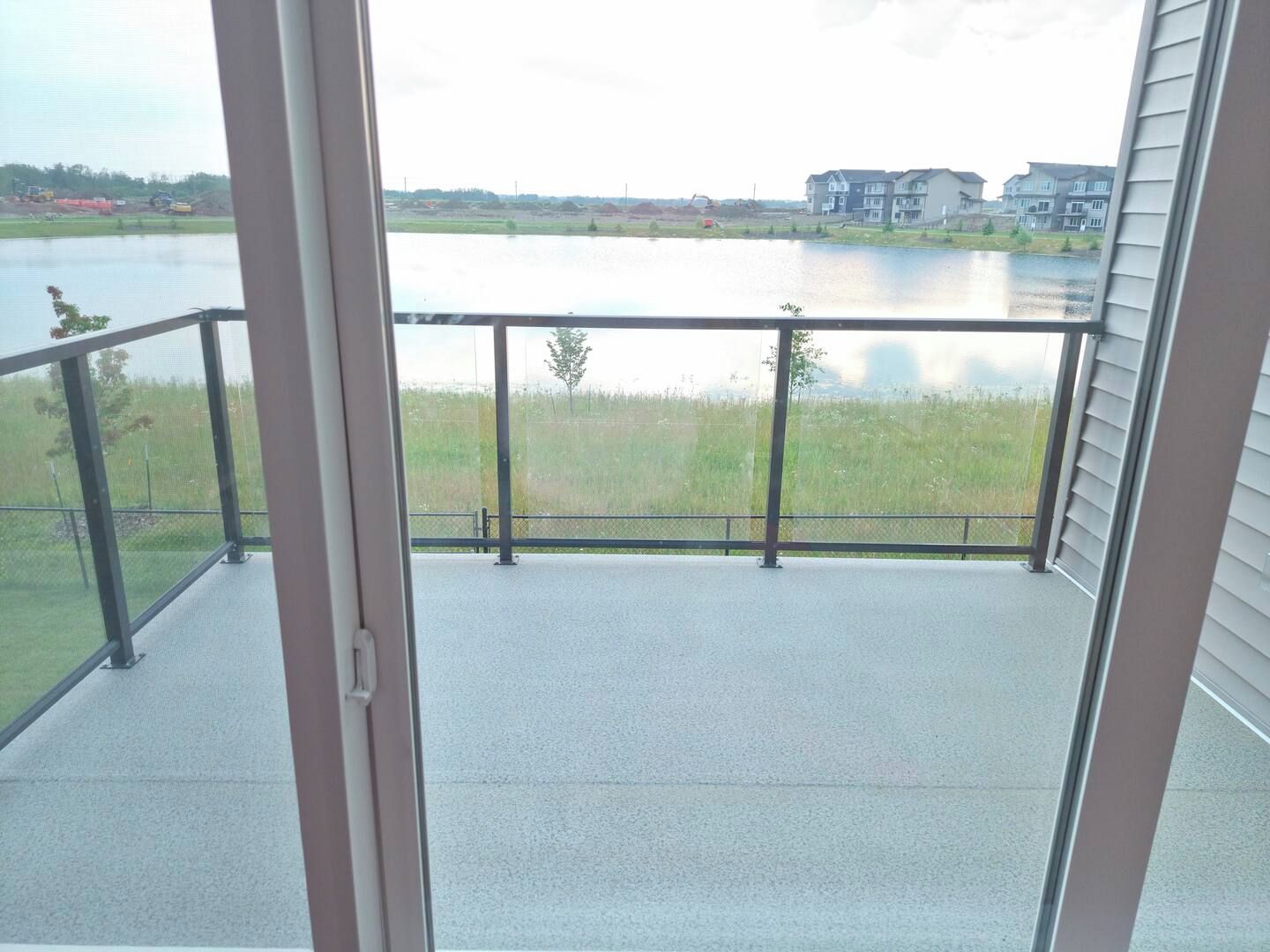 A balcony with a view of a lake and buildings in the distance.