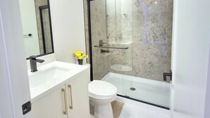 Un bagno moderno con cabina doccia in vetro, un water bianco e un mobile lavabo con specchio.