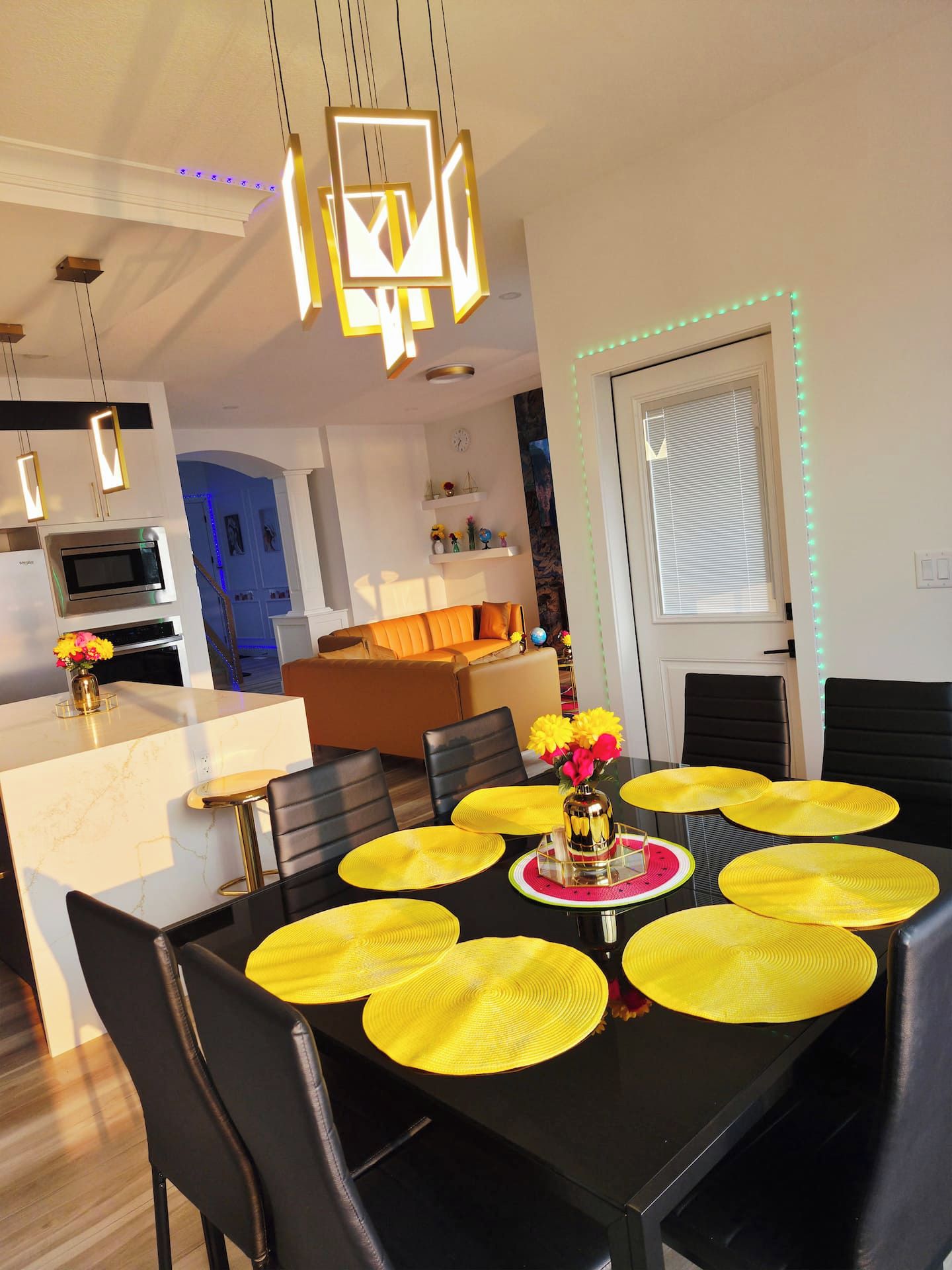 A modern dining area with a black table, yellow placemats, and a vase with flowers.