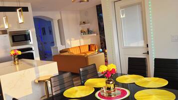 A modern dining area with a black table, yellow placemats, and a vase with flowers.