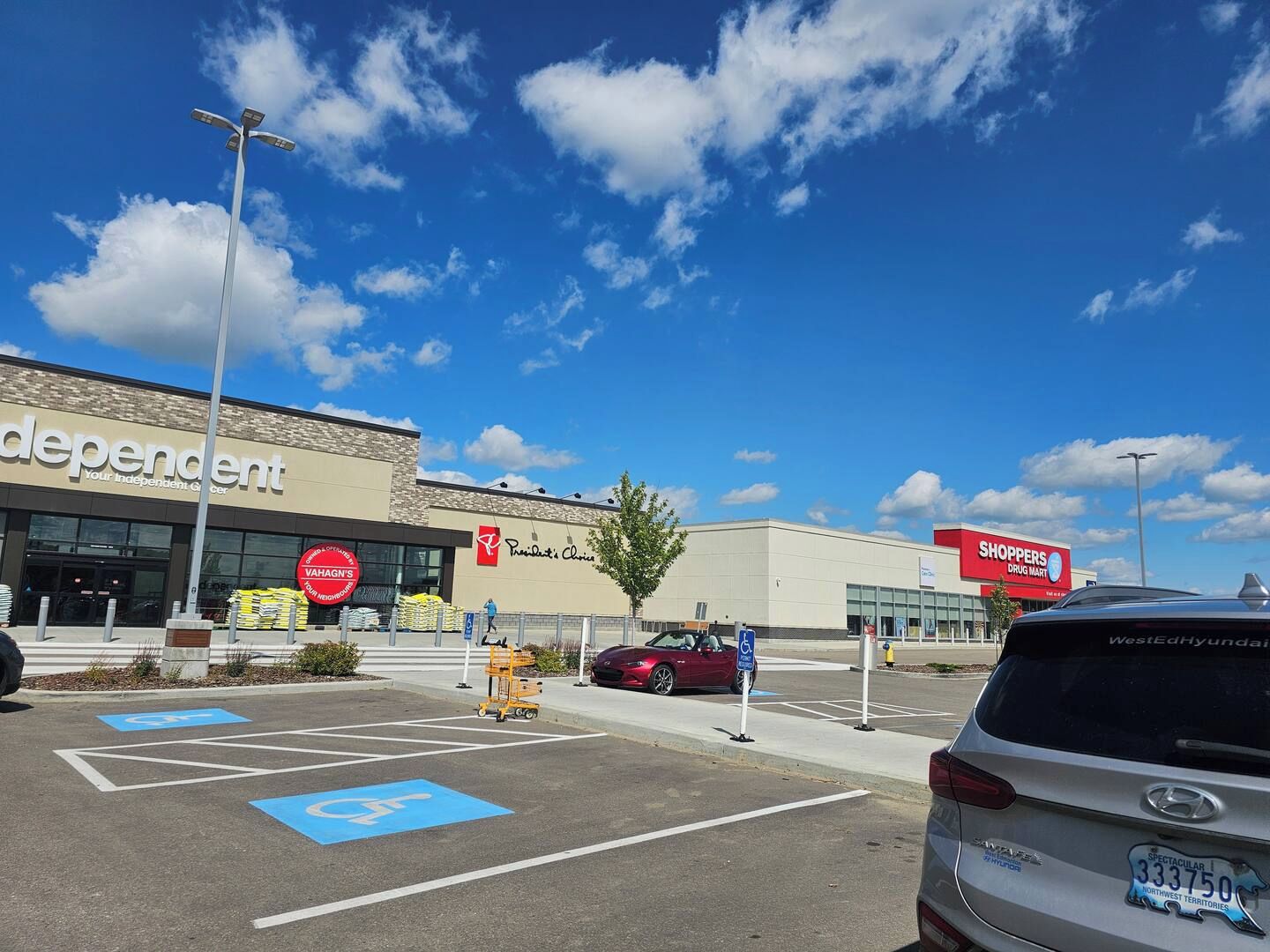 Um estacionamento com vagas para deficientes, uma farmácia e um supermercado.