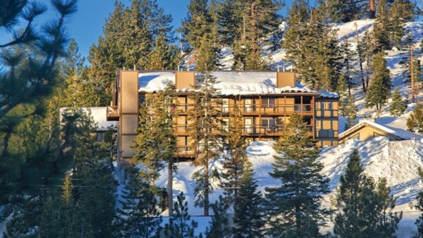 A lodge with a wooden exterior, surrounded by snow-covered mountains and pine trees. - WM BLOCK Lake Tahoe 1br - Tahoe 3 (Stateline)