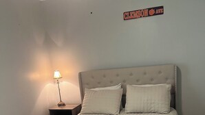Et soveværelse med en seng, et natbord, en lampe og et skilt på væggen.